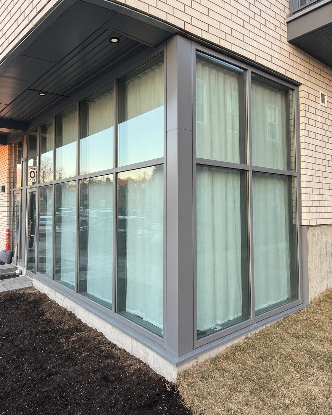 Corner windows before installation, with closed curtains visible behind the glass
